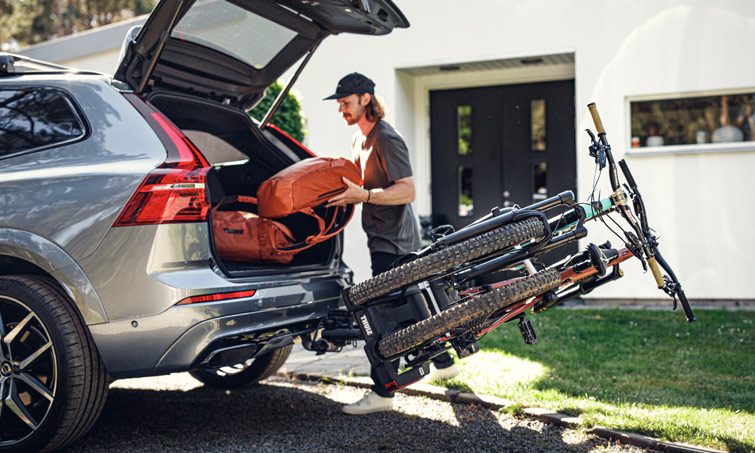 A-man-accesses-his-trunk-while-the-Thule-Easy-Fold-XT-towbar-bike-rack-still-have-the-bikes-loaded.jpg