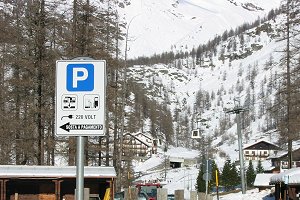 La funivia che porta agli impianti in quota, sullo sfondo della segnaletica di accesso all'area attrezzata